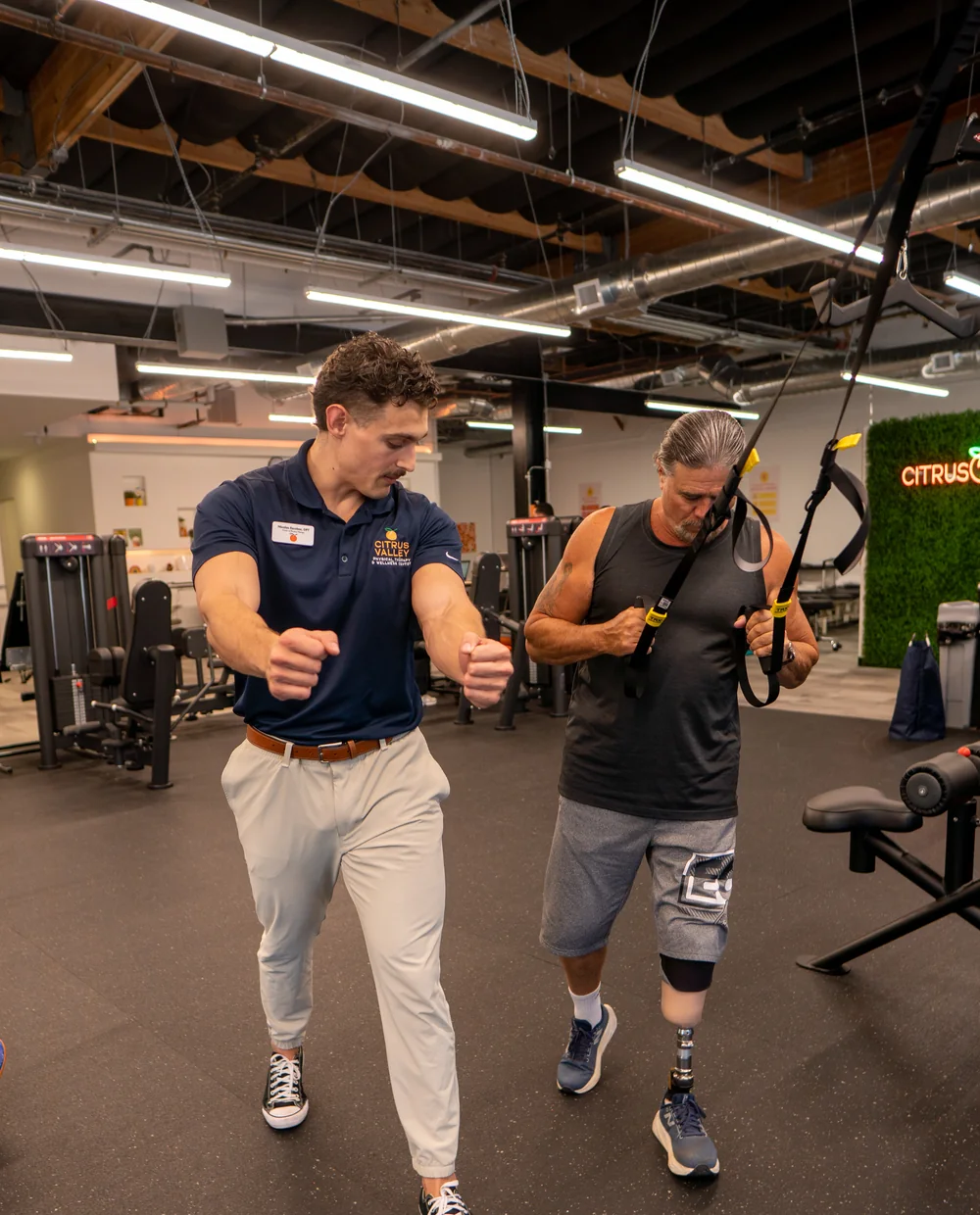 Physical therapist walking beside a patient with a prosthetic leg during gait training