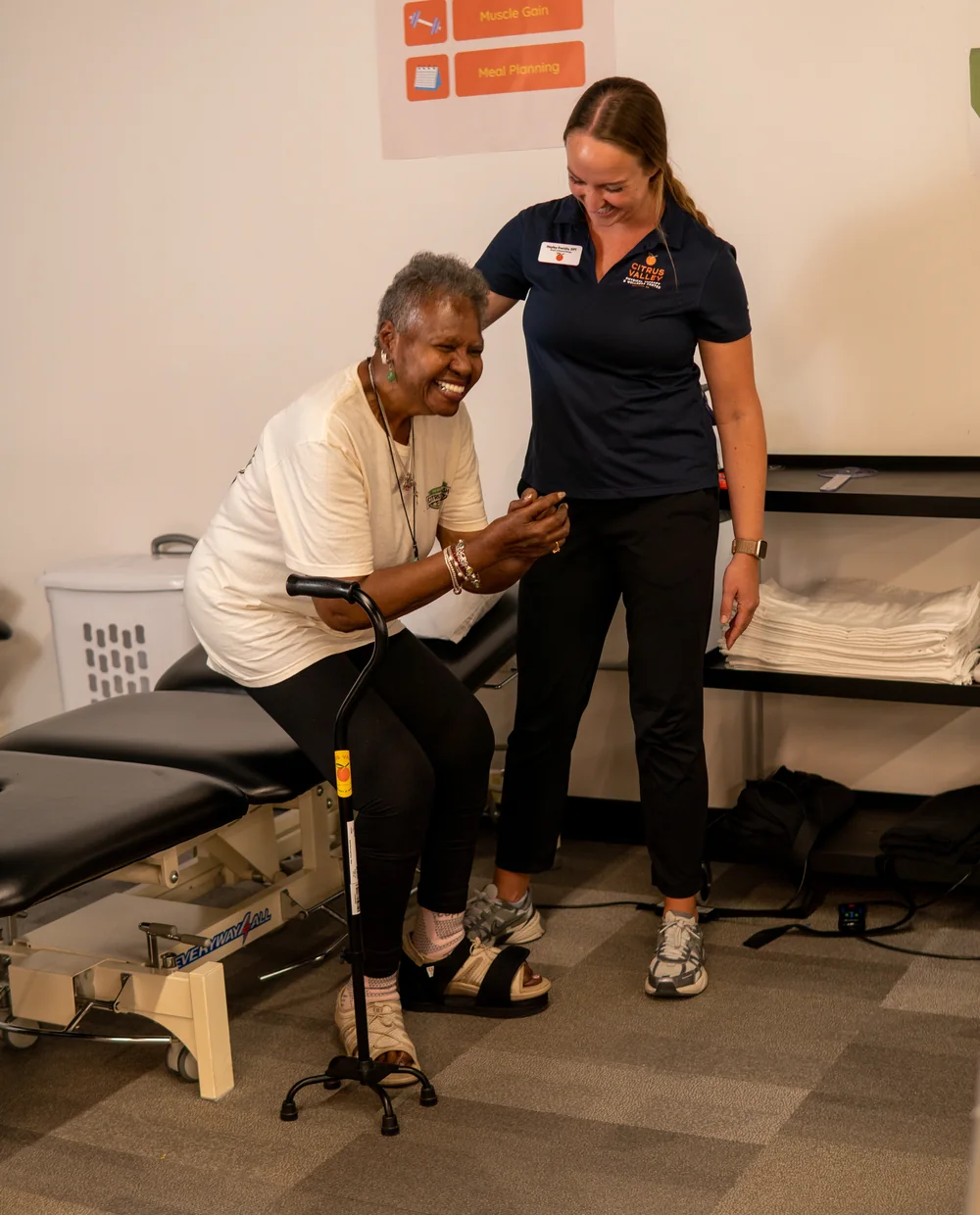 Physical therapist helping an older patient with a cane stand and walk