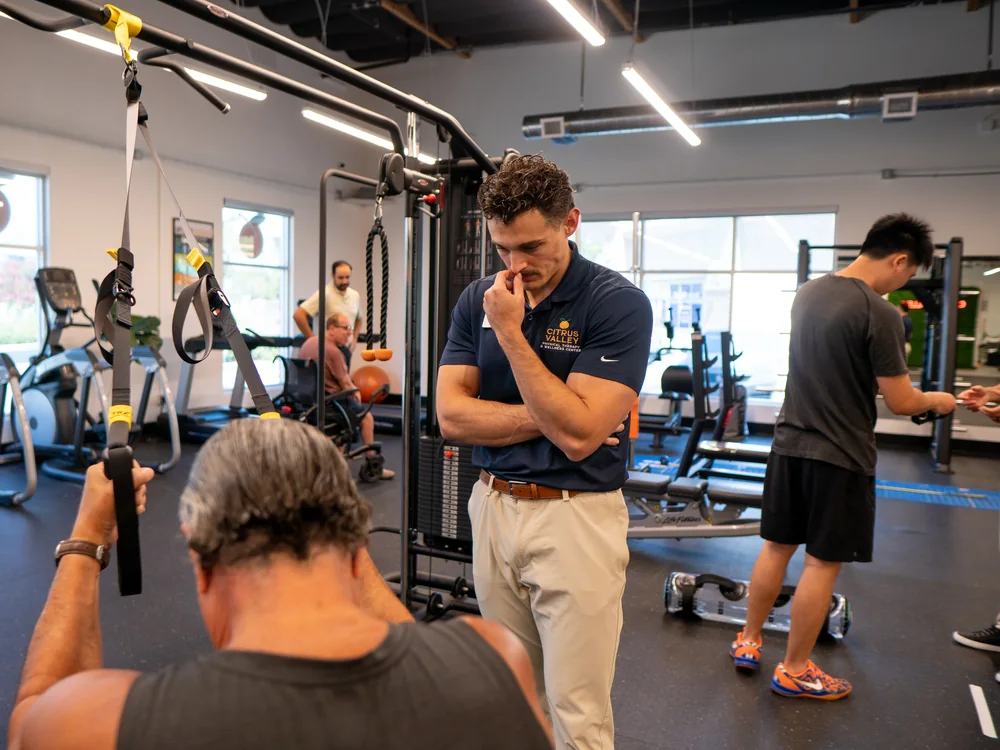 Therapist coaching a patient on suspension trainer straps in the Citrus Valley gym