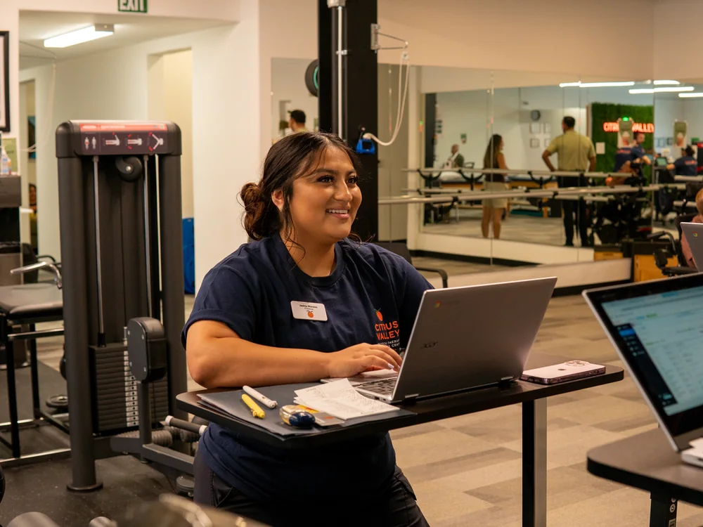 Citrus Valley team member smiling while working at a laptop on the clinic floor