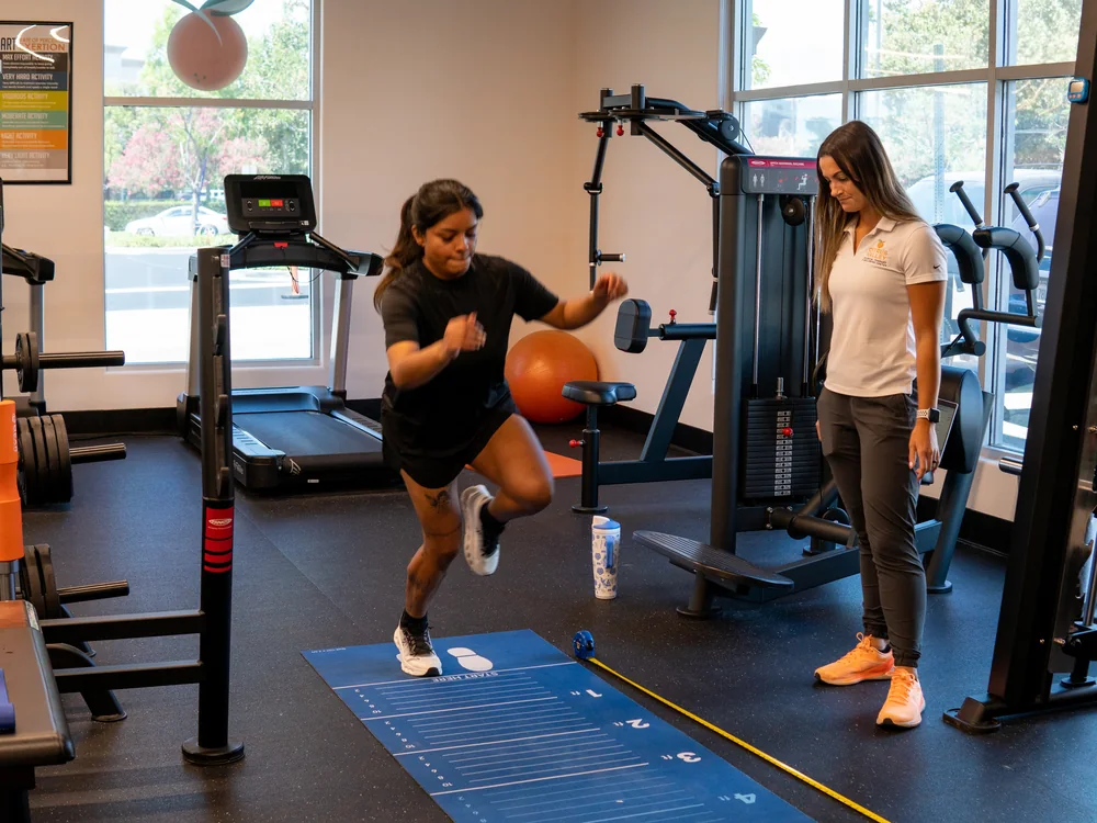 Physical therapist timing a patient's jump test on a measuring mat