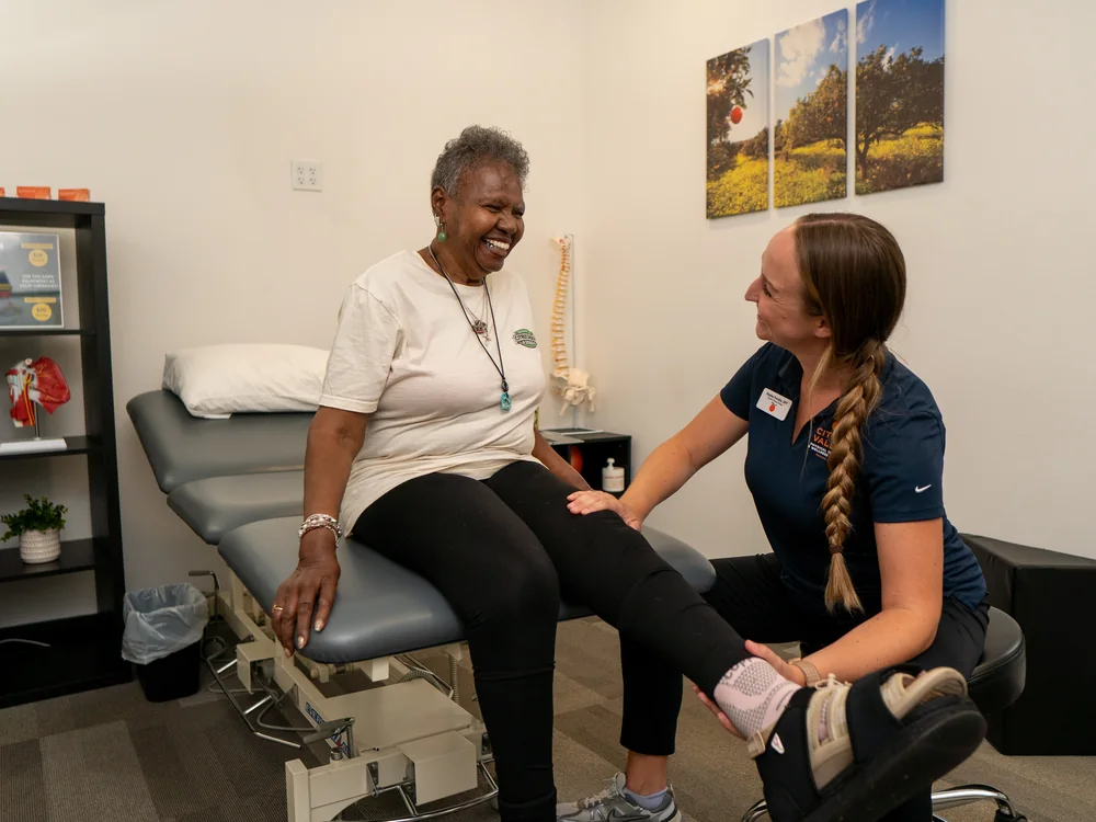 Physical therapist assessing a patient's ankle and knee while the patient laughs