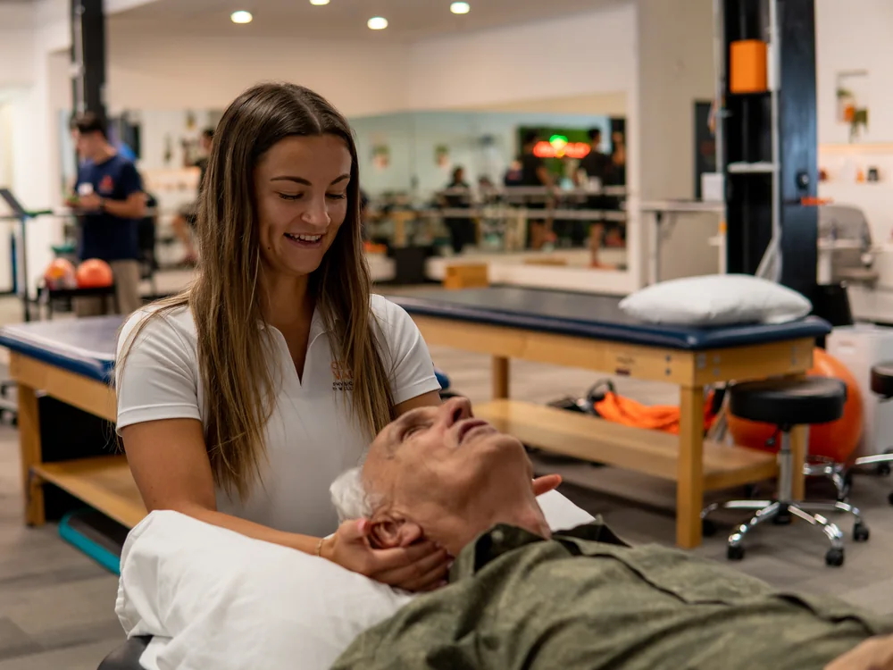 Physical therapist performing manual neck treatment on an older patient
